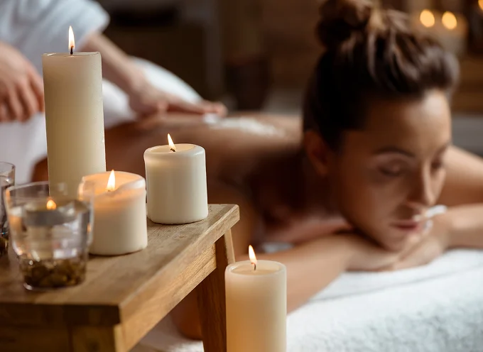 Woman receiving a relaxing massage in a spa setting with lit candles and soft ambient lighting