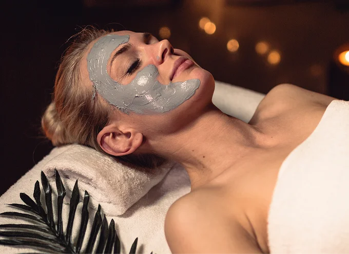 Woman with facial mask relaxing in spa setting, promoting skincare and wellness at Lalwa Aesthetics