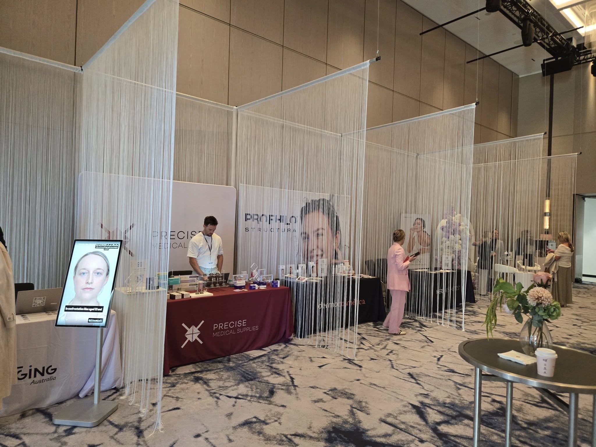 Aesthetic clinic booths at a medical or beauty expo with product displays, branding banners and attendees in a modern event space